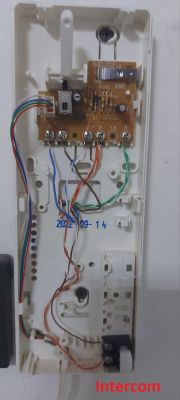 Wiring connections in a Urmet intercom Interior of a Urmet intercom with connected wires and visible circuit board.