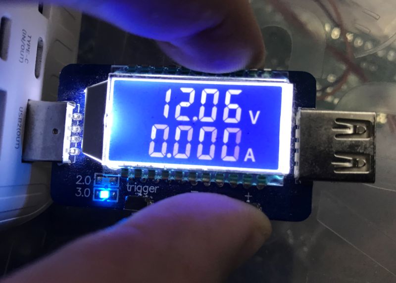 Wyświetlacz miernika USB pokazuje napięcie 12.06 V i prąd 0.000 A