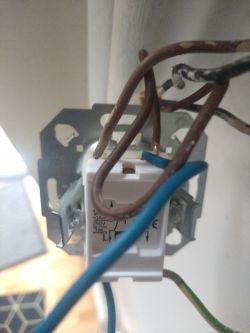 Podwójny włącznik elektryczny z widocznymi przewodami na ścianie.