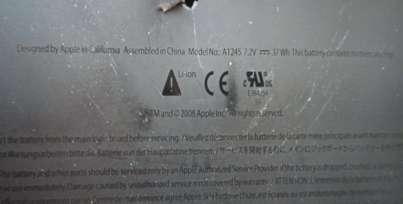 Zbliżenie na obudowę baterii Apple A1245 z widocznymi oznaczeniami i uszkodzeniem