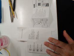 White desk with a temperature and humidity sensor manual and a hand holding a piece of packaging