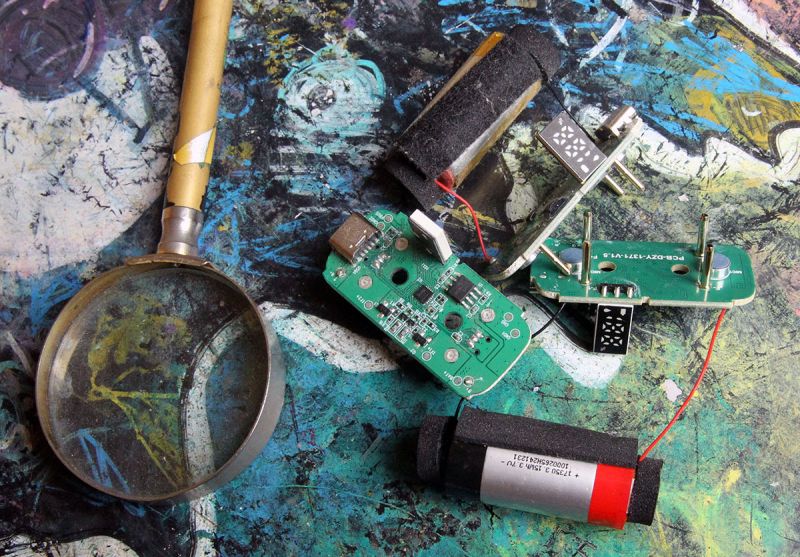 Rozebrany układ elektroniczny z płytkami PCB i baterią na kolorowym tle