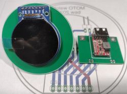 Okrągły moduł wyświetlacza na zielonej płytce PCB obok modułu przetwornicy z gniazdem USB