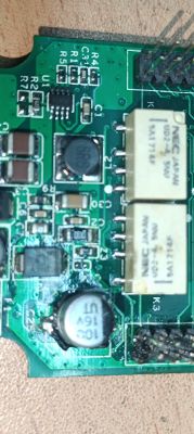 Zbliżenie na płytkę drukowaną z elementami elektronicznymi, w tym kondensatory i przekaźniki NEC.