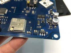 Close-up of a blue printed circuit board with visible integrated circuits, ESPRESSIF module, and electronic components.