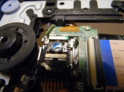 Wnętrze napędu CD/DVD ROM z widocznym modułem lasera i elektroniki.