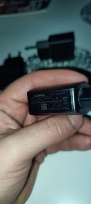 Ładowarka Huawei trzymana w dłoni z widocznymi parametrami.
