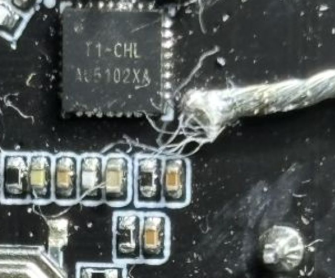 Close-up of a PCB showing an IC and a cluster of fine fibers near a soldered area