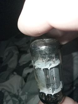 Lampa elektronowa trzymana w palcach, zbliżenie na jej wnętrze z widocznymi elektrodami