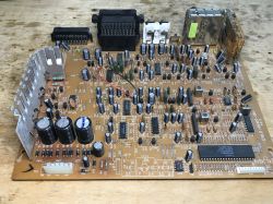 Płytka PCB z wieloma układami scalonymi i kondensatorami na drewnianym blacie.