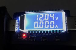 Wyświetlacz testera USB pokazujący napięcie 12.04 V i prąd 0.000 A.