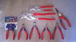 Zestaw narzędzi Knipex z czerwono-niebieskimi uchwytami, w tym szczypce i obcęgi.