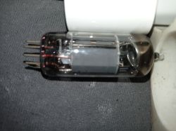 Lampa elektronowa z ośmioma pinami leży na ciemnym materiale obok białego przedmiotu