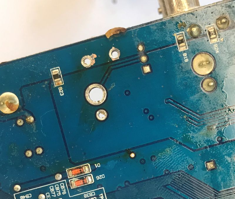 Close-up of a blue PCB with solder pads, vias, traces, and labels B23, B19, B24