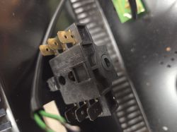 Zbliżenie czarnego przełącznika elektrycznego z metalowymi konektorami, fotografowanego wewnątrz obudowy