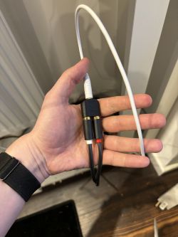 Ręka trzymająca przejściówkę RCA-Jack z podłączonym kablem Jack 3,5 mm.