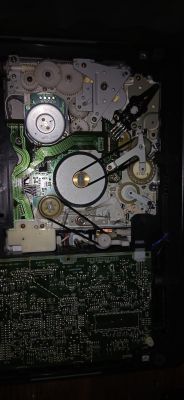 Wnętrze mechanizmu urządzenia z kołami zębatymi, taśmą i płytkami PCB, ujęcie z góry