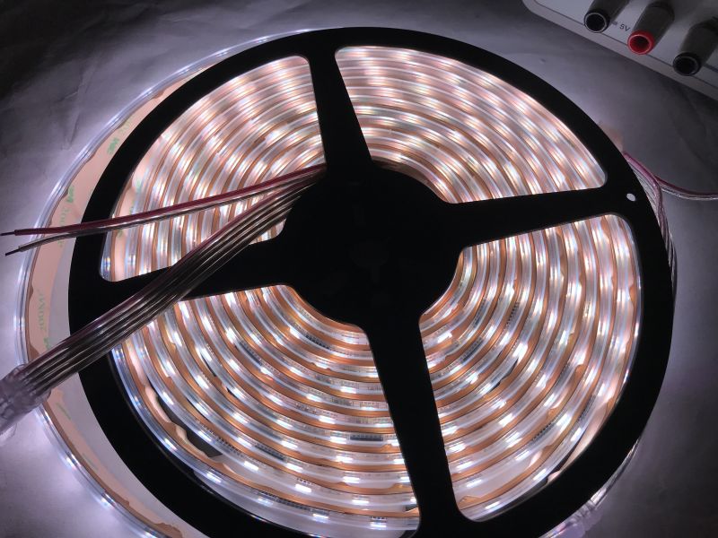 Illuminated RGBW LED strip coiled on a reel and prepared for wiring.