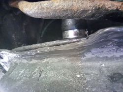 Section of a metal fuel tank with visible sealant repair and a hose clamp.