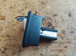 Black plastic socket with exposed wires on a wooden table.