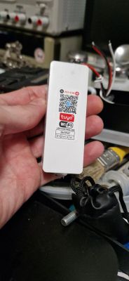 Tuya WiFi LED Controller in Hand Person holding a Tuya LED controller with WiFi label and QR code.