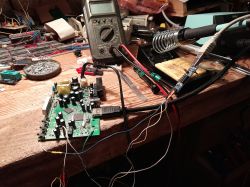 Tuner circuit board with USB-UART module and multimeter on workbench