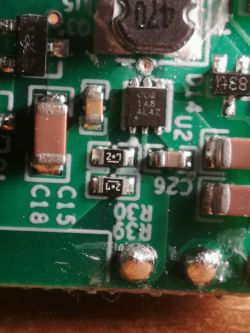 Zbliżenie płytki PCB z elementami SMD i cewką; układ z oznaczeniem „1A8 AL4Z” obok.
