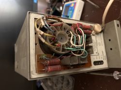 Tył otwartego urządzenia elektronicznego z widocznymi kablami i komponentami.
