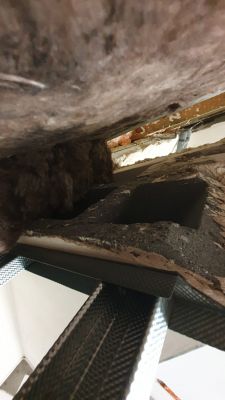 Otwór kominowy w warstwie izolacyjnej z widoczną wełną mineralną.
