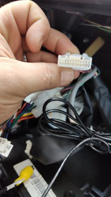 Złącze 24-pinowe trzymane w ręce z przewodami w tle.