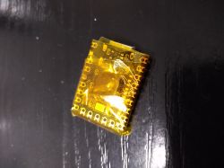 Small PCB wrapped in yellow electrical tape lying on a black surface