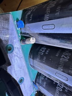 Zdjęcie wnętrza urządzenia elektronicznego z widocznymi kondensatorami i elementami na zielonej płytce drukowanej.