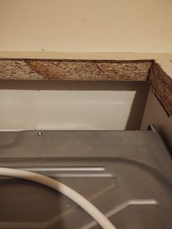 Widok na fragment blatu kuchennego oraz tylną część piekarnika z widocznym kablem.