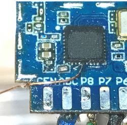 Close-up of an electronic module with a thin wire soldered to a pin.