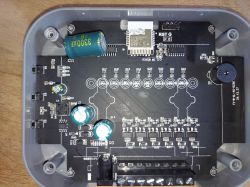 PCB inside a gray enclosure with capacitors, a radio module, a buzzer, and a screw terminal block