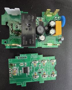 Two PCB boards with a relay, capacitors, and multiple push buttons on a black surface