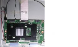 Płyta elektroniczna z podłączonymi przewodami i taśmą w środku urządzenia.