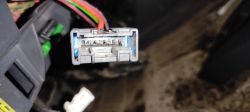 Zbliżenie na plastikową wtyczkę elektryczną z widocznymi stykami i kolorowymi przewodami
