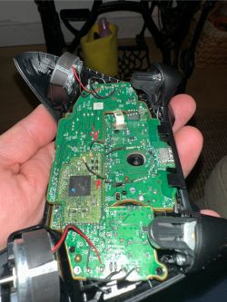 Wnętrze rozkręconego kontrolera z widoczną płytą główną i podłączonymi kabelkami.