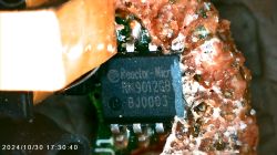 Close-up of a Reactor-Micro RM9012GB chip on a PCB, partially covered by brown resin.