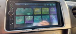 Ansicht eines Multimedia-Systems im Auto mit Touchscreen, auf dem verschiedene Apps und Funktionen angezeigt werden.