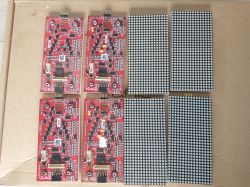 Sześć czerwonych płytek PCB i sześć czarno-białych modułów matryc LED 16x16 na kartonie