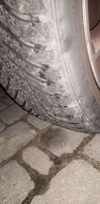 Zdjęcie opony samochodowej z poszarpanym bieżnikiem na zewnętrznej części.