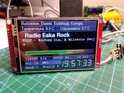 TFT display module showing “Radio Eska Rock,” temperature readings, and a digital clock on a work mat