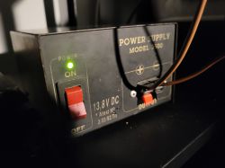 Zasilacz model 3500, 13,8V DC, włączony, widoczny przełącznik i przewody