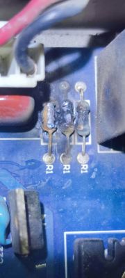 Zdjęcie trzech przypalonych rezystorów na płytce PCB z oznaczeniami R1.