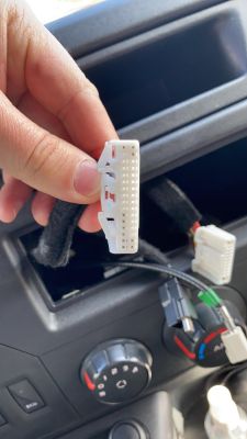 Nahaufnahme einer Hand, die einen weißen Autoradiostecker hält.