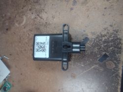 Black plastic airflow sensor with a QR code label on a dirty metal work surface