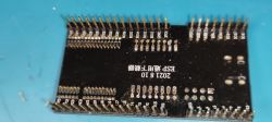 Photo of a circuit board with protruding pins and technical markings.