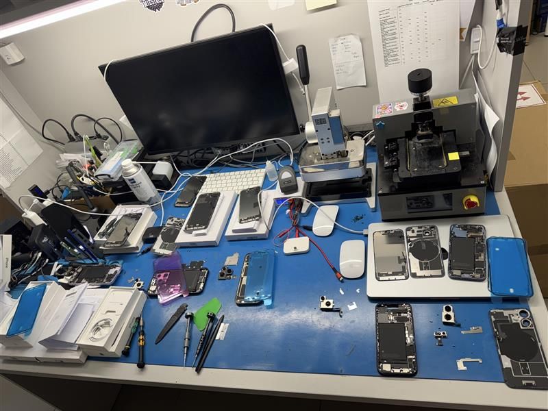 Stanowisko serwisowe z rozebranymi telefonami i narzędziami do naprawy